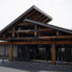 Wooden entrance canopy with metal brackets over a storefront, featuring glass doors beneath.