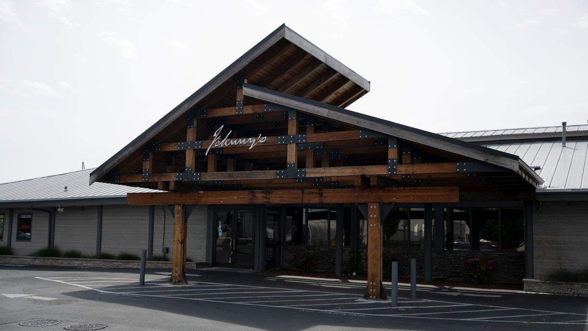 Wooden entrance canopy with metal brackets over a storefront, featuring glass doors beneath.
