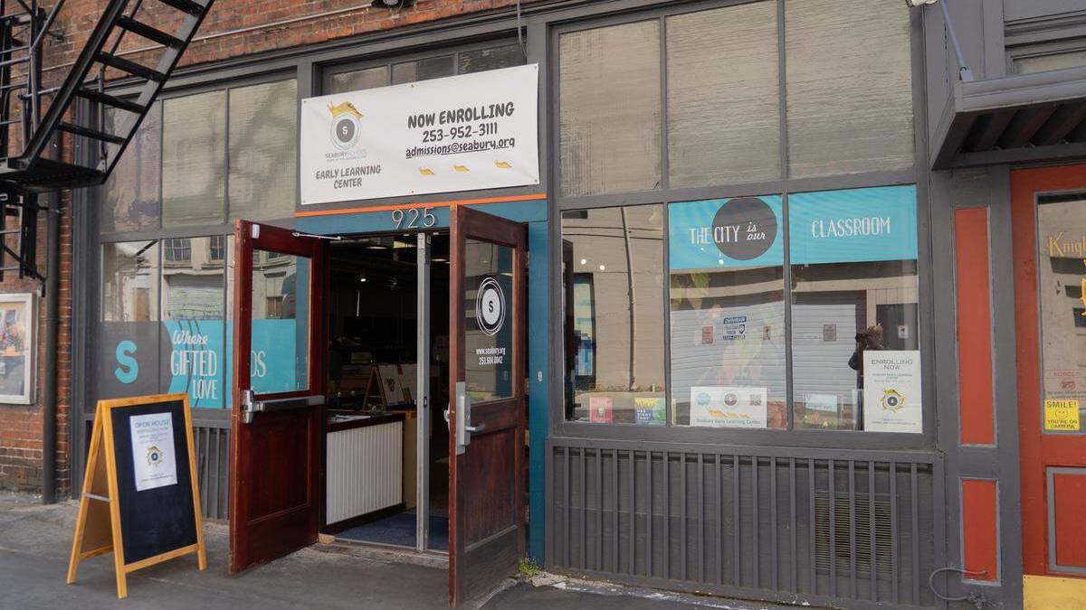 Open storefront of a learning center with a 'Now Enrolling' banner and blue window decals reading 'The City in a Classroom.'