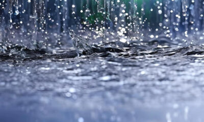 Close-up of raindrops striking a dark, choppy water surface with droplets suspended in midair.