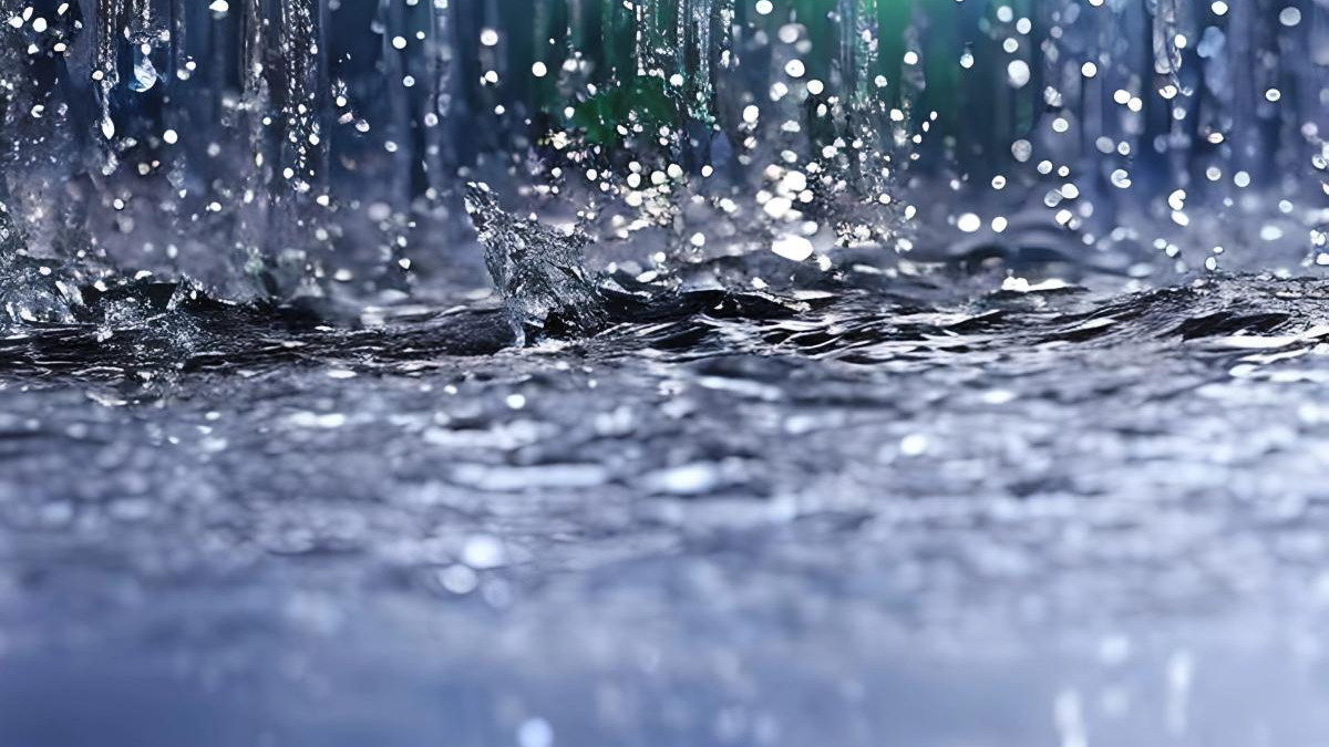 Close-up of raindrops striking a dark, choppy water surface with droplets suspended in midair.