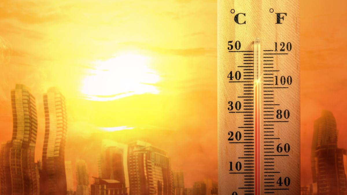 Thermometer showing high temperature beside a sunlit city skyline, suggesting a heatwave.
