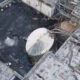 Aerial view of an industrial plant with a toppled circular tank, dark liquid on the ground and scattered debris among pipes and walkways.