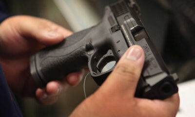 Close-up of a person gripping a black handgun with both hands, focusing on the grip and trigger area.