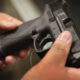 Close-up of a person gripping a black handgun with both hands, focusing on the grip and trigger area.