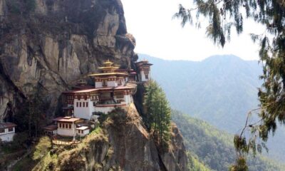 Tiger's Nest Monastery perched on a rocky cliff with pine trees and a forested valley in the distance.