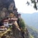 Tiger's Nest Monastery perched on a rocky cliff with pine trees and a forested valley in the distance.