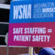 Blue and pink protest sign reading 'WSNA Washington State Nurses Association' and 'Safe staffing = patient safety'.