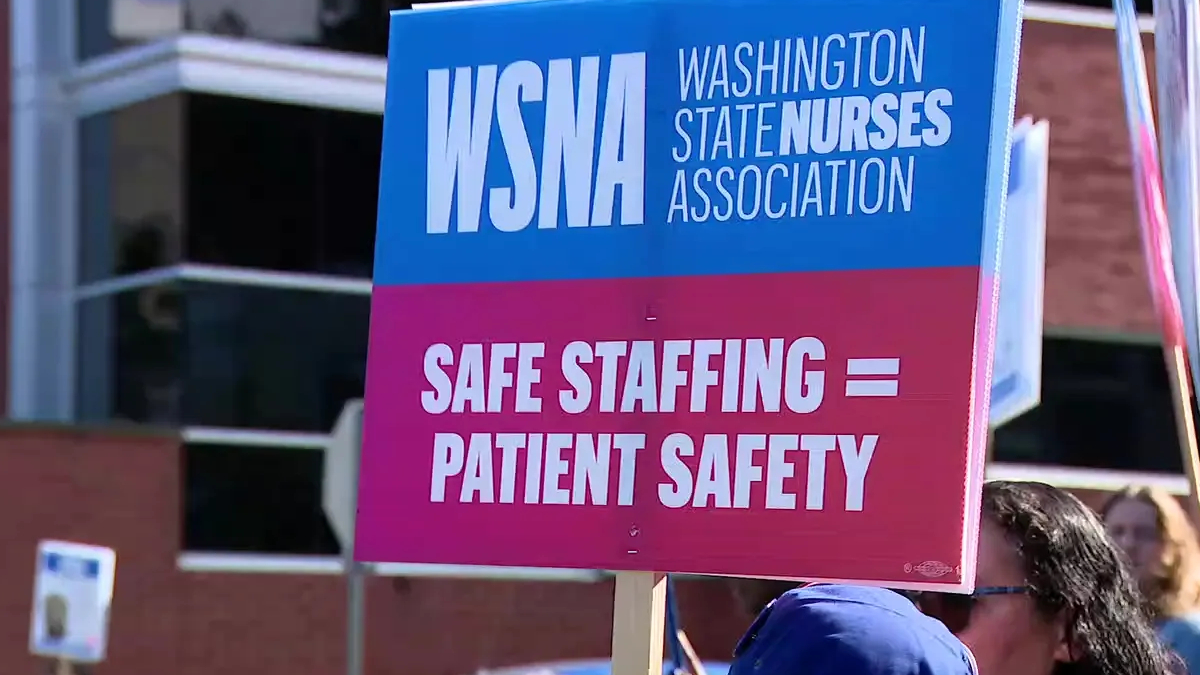 Blue and pink protest sign reading 'WSNA Washington State Nurses Association' and 'Safe staffing = patient safety'.