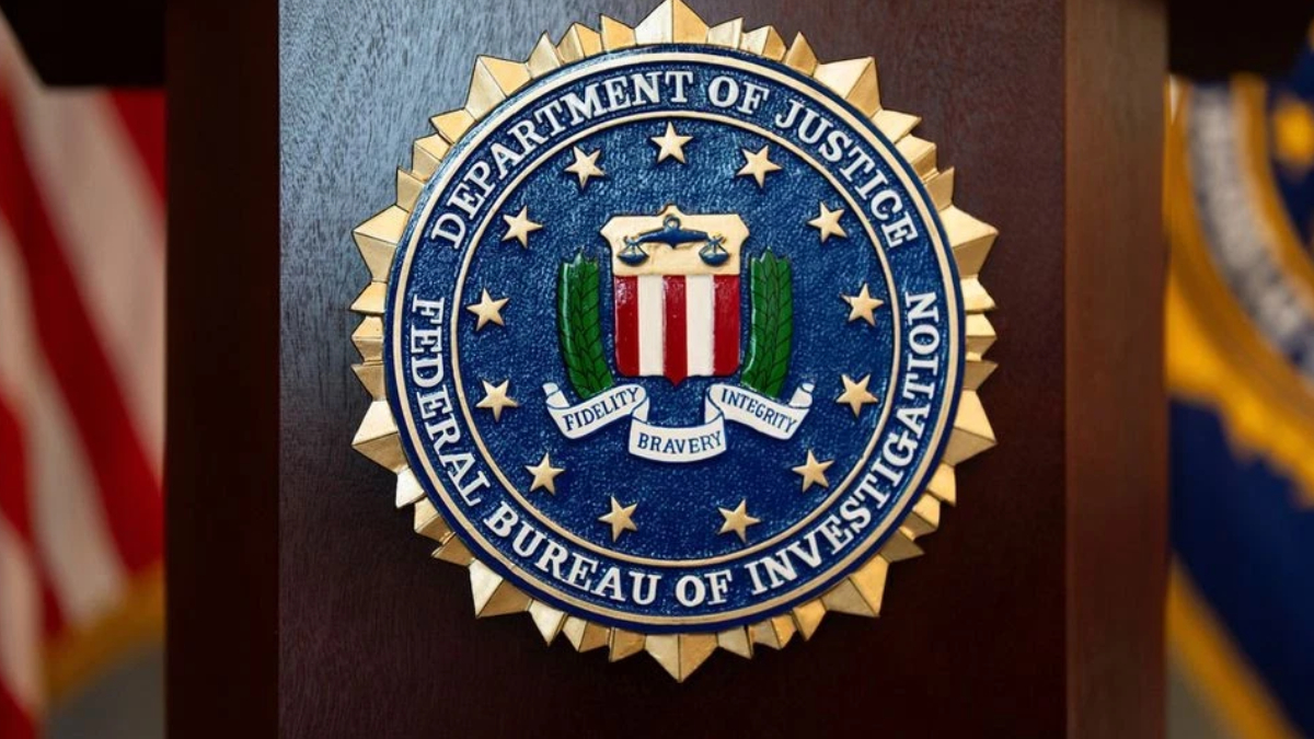 FBI seal mounted on a wooden podium with blurred American flags in the background.