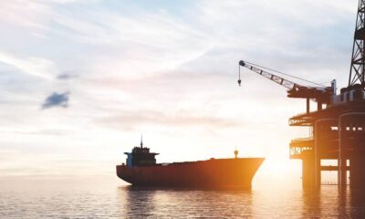 Cargo ship near an offshore oil platform at sunset, calm water reflecting warm light.
