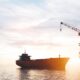 Cargo ship near an offshore oil platform at sunset, calm water reflecting warm light.