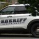 White sheriff's patrol SUV with 'SHERIFF' and 'PIERCE COUNTY' on the side, parked beside trees.