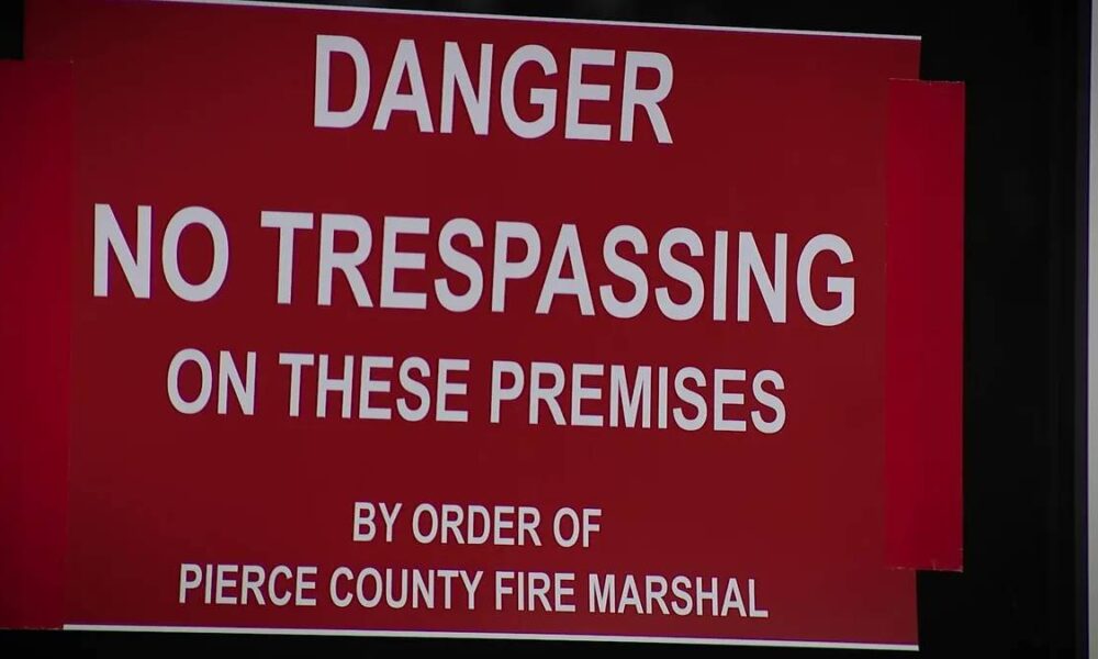 Red warning sign: "DANGER NO TRESPASSING ON THESE PREMISES" by order of Pierce County Fire Marshal on a dark background.