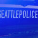 Side view of a Seattle Police Department patrol car with bold 'SEATTLEPOLICE' lettering and the department shield.