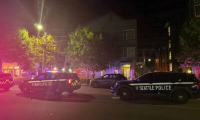 Night scene of Seattle Police Department vehicles with flashing red and blue lights blocking a street at night.