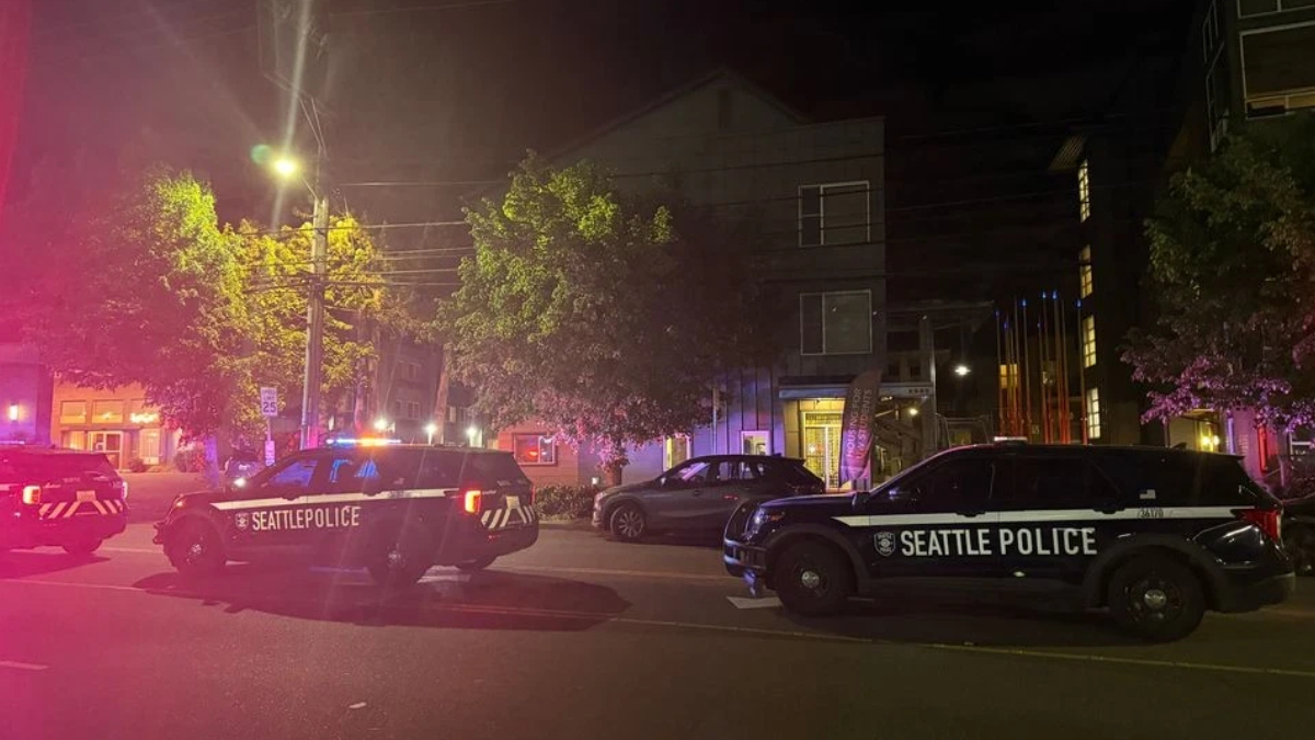 Night scene of Seattle Police Department vehicles with flashing red and blue lights blocking a street at night.