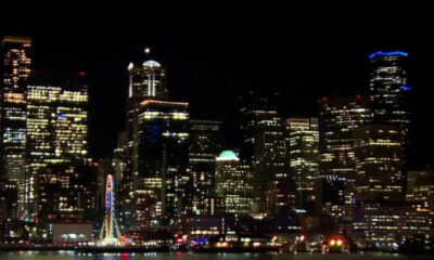 Night city skyline at night with illuminated skyscrapers along the waterfront and a lit ferris wheel by the water.