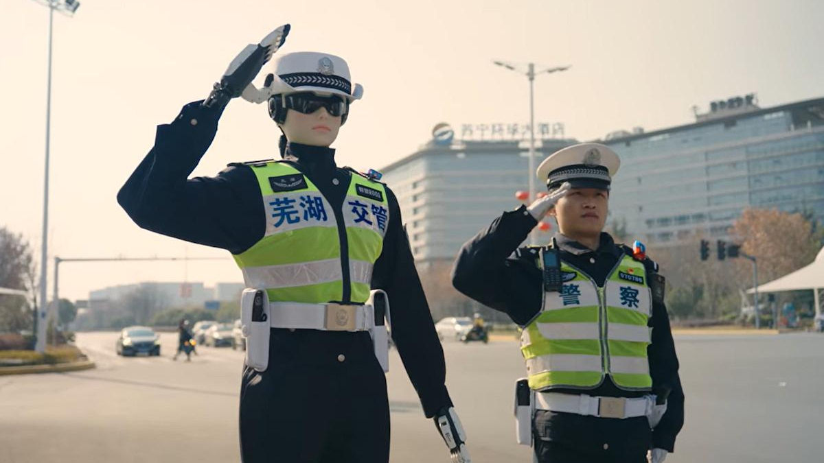 Two police officers in reflective vests saluting while standing in the street, directing traffic.