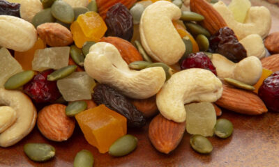 Trail mix with cashews, almonds, pumpkin seeds and assorted dried fruits on a brown surface.