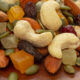 Trail mix with cashews, almonds, pumpkin seeds and assorted dried fruits on a brown surface.