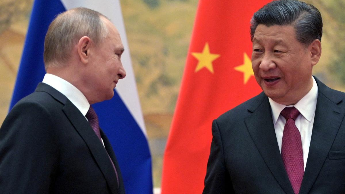 Putin and Xi Jinping in dark suits speaking to each other, with the Russian and Chinese flags in the background.