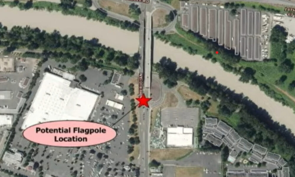 Aerial map marking a potential flagpole location with a red star on a road beside a river; pink label reads 'Potential Flagpole Location' nearby.