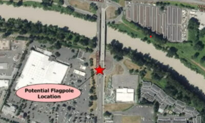 Aerial map marking a potential flagpole location with a red star on a road beside a river; pink label reads 'Potential Flagpole Location' nearby.