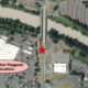 Aerial map marking a potential flagpole location with a red star on a road beside a river; pink label reads 'Potential Flagpole Location' nearby.