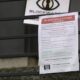 Flyer taped to a metal railing with a red headline asking for help to save 14th Ave W, featuring a logo above and a QR code at the bottom.