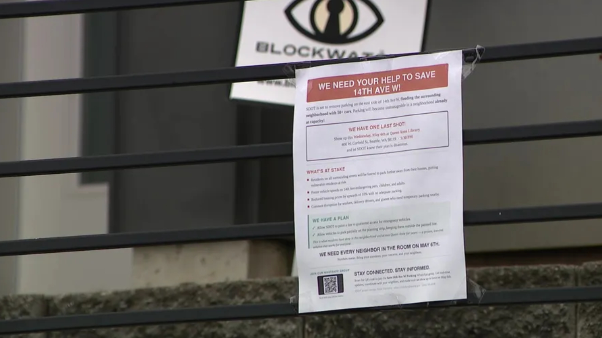 Flyer taped to a metal railing with a red headline asking for help to save 14th Ave W, featuring a logo above and a QR code at the bottom.