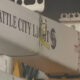 Close-up of a utility crane arm labeled Seattle City Light with a yellow safety strap and metal hooks visible on the side.