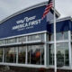 Exterior of the America First Credit Union branch with a blue curved roof and large glass windows, flagpole with an American flag outside.