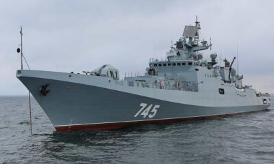 Grey naval warship with hull number 745 on calm sea under a cloudy sky, bow to the left.