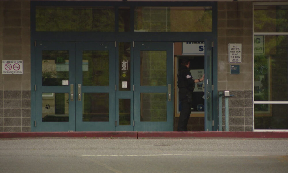 Uniformed officer standing at an open service window inside a storefront entrance.