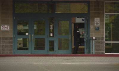 Uniformed officer standing at an open service window inside a storefront entrance.