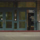 Uniformed officer standing at an open service window inside a storefront entrance.