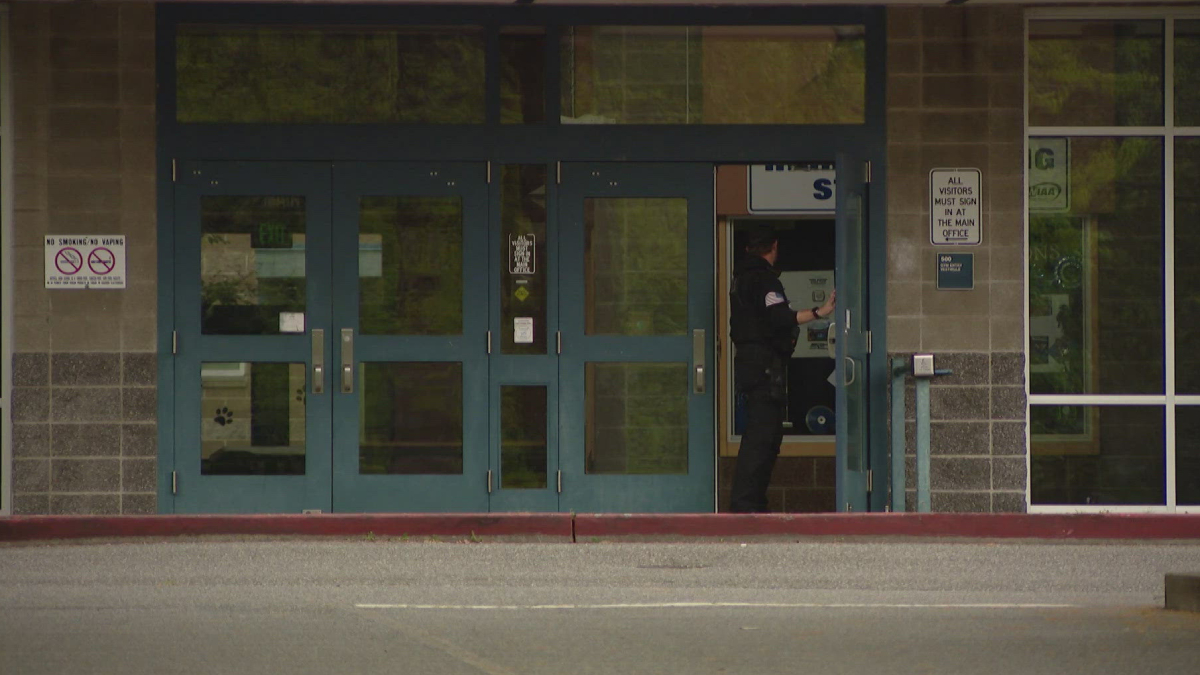 Uniformed officer standing at an open service window inside a storefront entrance.