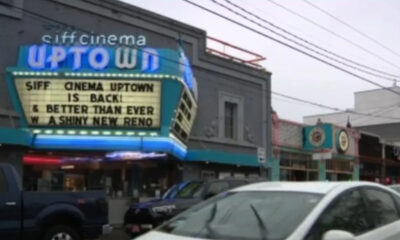 Marquee sign for SIFF Cinema Uptown announcing 'SIFF CINEMA UPTOWN IS BACK & BETTER THAN EVER' on a busy street.