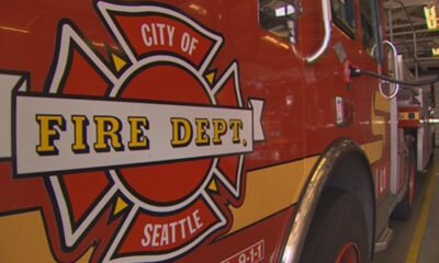 Red fire department fire engine with a Seattle Fire Dept logo and the words 'FIRE DEPT.' visible on the side, indoors in a station.