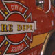 Red fire department fire engine with a Seattle Fire Dept logo and the words 'FIRE DEPT.' visible on the side, indoors in a station.