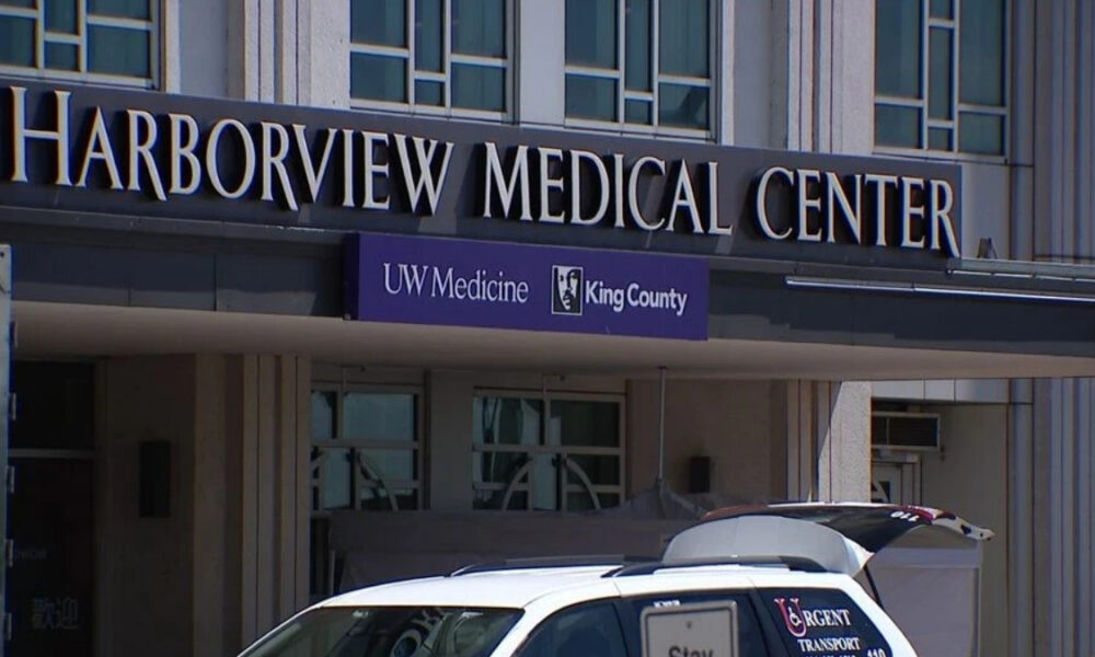 Facade of Harborview Medical Center with UW Medicine King County banner and a white transport van in front.
