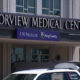 Facade of Harborview Medical Center with UW Medicine King County banner and a white transport van in front.