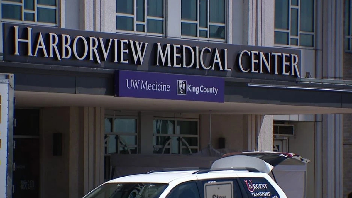 Facade of Harborview Medical Center with UW Medicine King County banner and a white transport van in front.