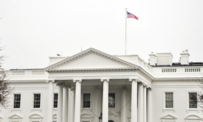 Front view of the White House with a neoclassical portico and an American flag on a flagpole
