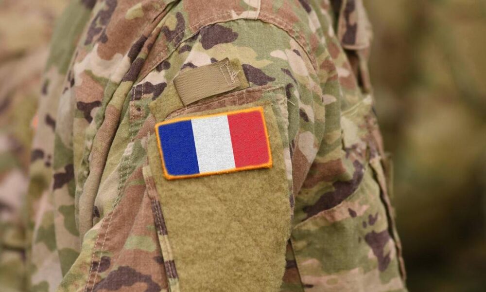 Soldier in camouflage uniform with a French flag patch on the sleeve.