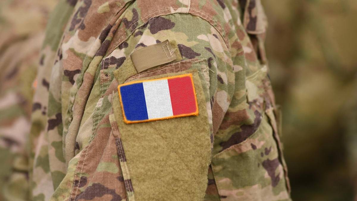 Soldier in camouflage uniform with a French flag patch on the sleeve.