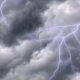 Dark storm clouds with bright jagged lightning bolts streaking across the sky.