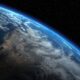Earth's curved horizon from space, with blue atmospheric glow and starry backdrop