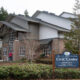 Municipal Civic Center building with stone columns and a blue 'Civic Center' sign in front listing Administration, Court, Police, and Community Development in Gig Harbor.